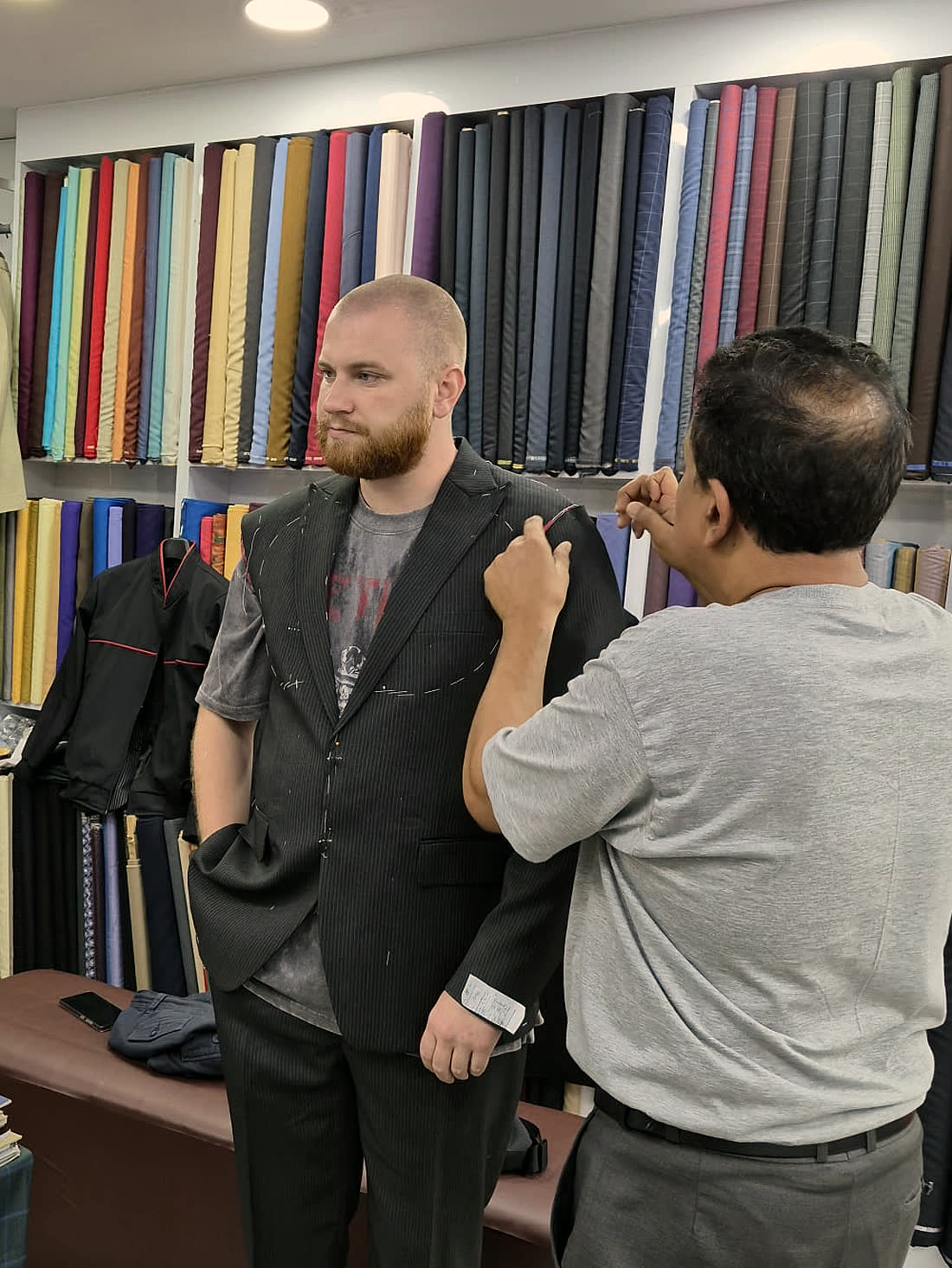 A tailor marking the shoulder of a waistcoat on the guest wearing it