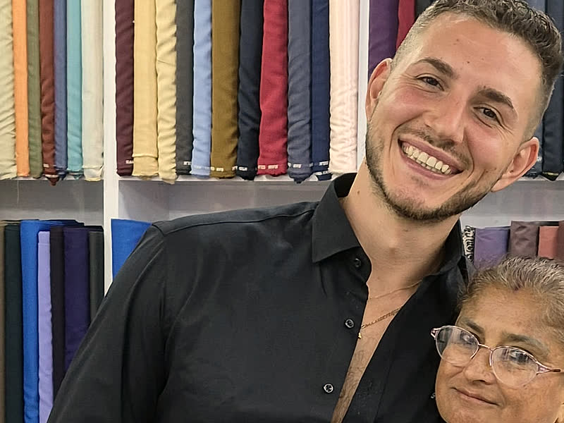 A guest in a made-to-measure black shirt, in front of the shirting shelves